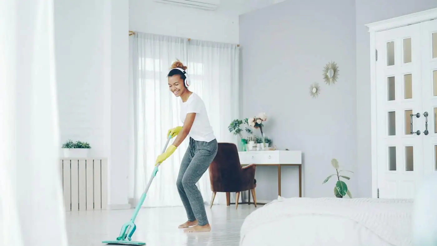 A carer in gloves disinfecting an empty pet room with a mop